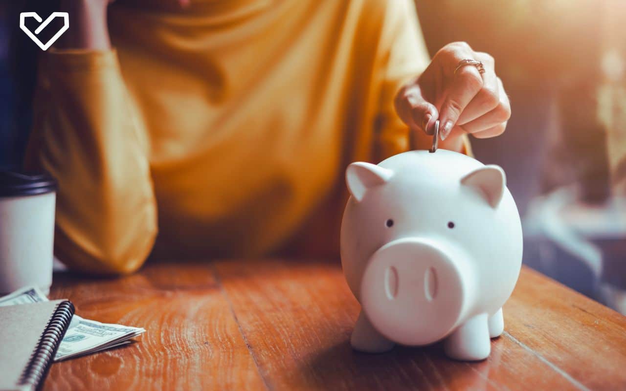 woman with coffee putting money in piggy bank